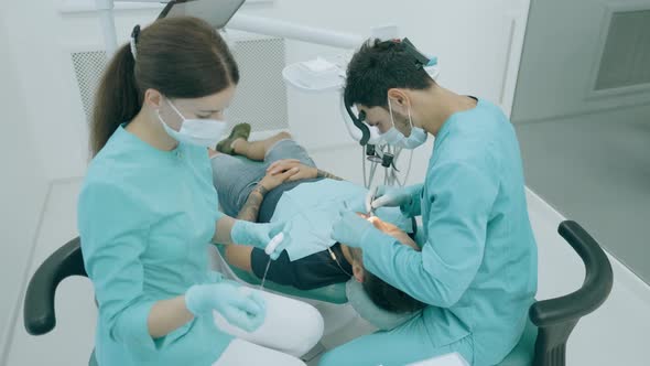 Dentist with Nurse and Patient in Dentist Office. A Patient Getting Dental Treatment at Dental