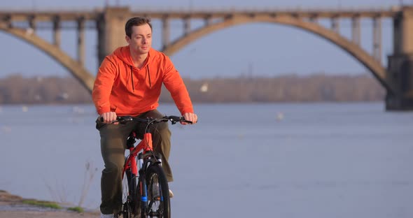 Bicyclist Riding Bike at River Embankment Slow Motion