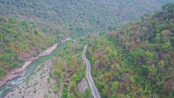 Mountain Road Meanders Along Rocky River in Tropical Highland