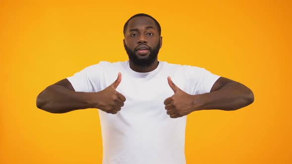 Handsome Black Man Smiling Confidently, Showing Thumbs Up on Yellow Background