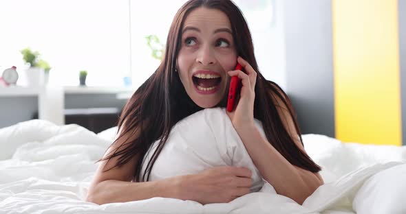 Happy Young Woman Talking on Phone While Lying in Bed Closeup