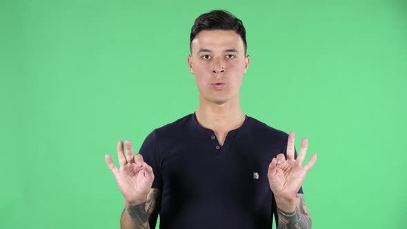 Portrait of a Handsome Young Guy Is Looking at the Camera Relaxing and Meditating. Green Screen.