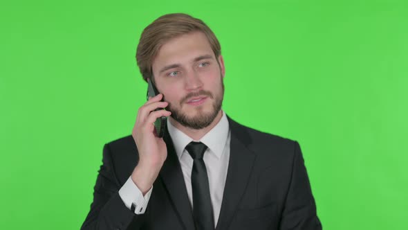 Young Businessman Talking on Phone on Green Background