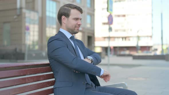 Businessman Smiling at Camera while Sitting on Bench