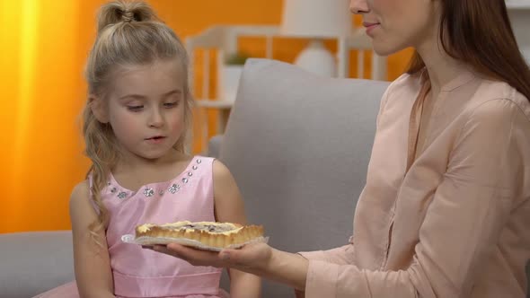 Young Mom Giving Surprised Little Girl in Princess Dress Sweet Cake, Celebration