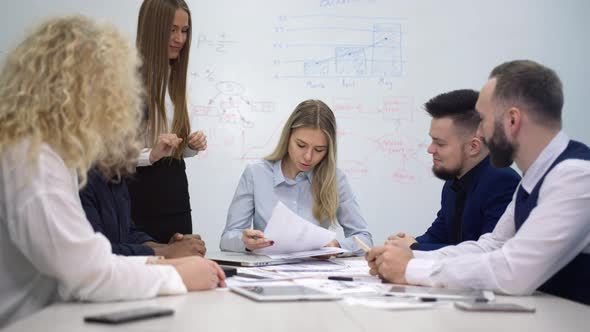 Businesswoman Sitting at Multiethnic Team Meeting at Office Signing Contract or Important Documents