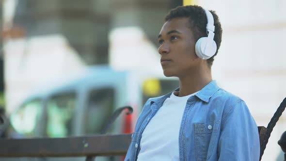 Sad Mixed-Race Boy Listening to Favourite Romantic Song, Yearning on Bench