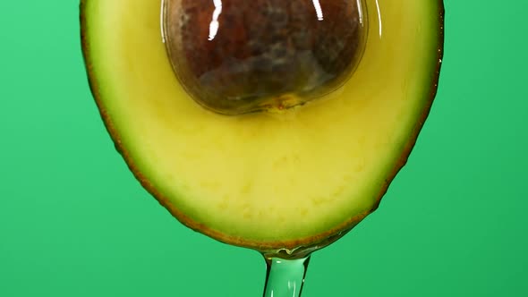 Slow Motion Closeup of Fresh Avocado Fruit and Oil Flowing on Green Background