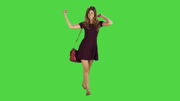 Casual Young Woman Dances and Goofing Around While Walking Over a Green Screen