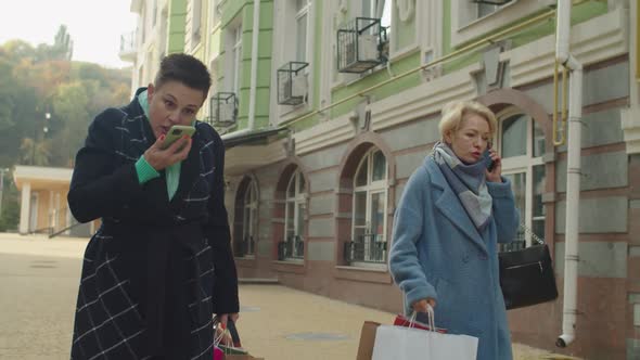 Two Annoyed Mature Women Having Argument Talking Via Phone Outdoors