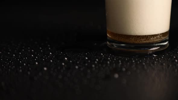 Close up pouring beer with bubbles and foam in glass on black background