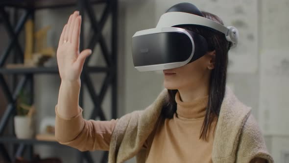 Female Engineer in Virtual Reality Helmet with Hands Imitates Work of Interface