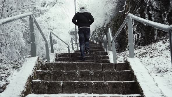 Unrecognizable man walking up frozen steps