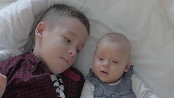 Boy and His Baby Sister Lying on a Bed