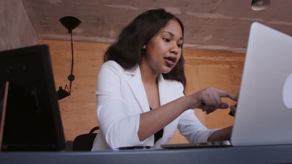 Black Business Woman Counts on a Calculator and Makes Notes