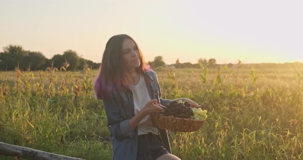 Basket with Harvest of Grapes in Hands of Young Girl