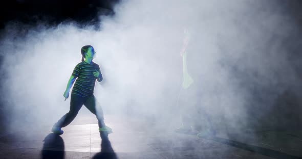 Two young female dancers performing hip hop dance in with light and smoke background