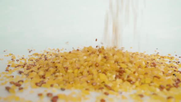 Mixture of Corn and Chia Seeds Pouring Onto White Surface