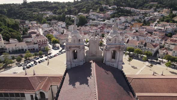 Baroque style church towers, Monastery of Alcobaça, against cityscape. Orbiting view