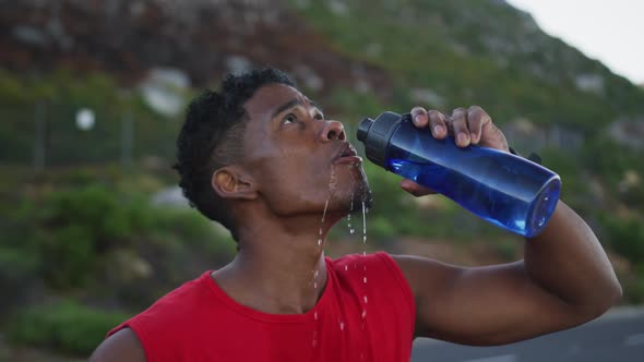 African american man drinking water while standing on the road