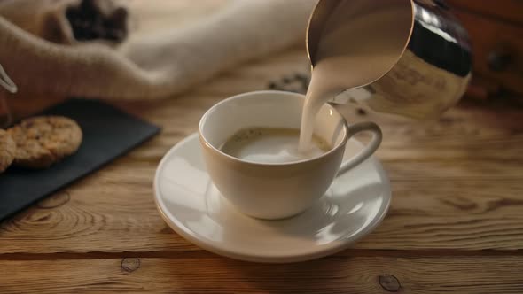 Pouring Foamed Milk Into Coffee Cup in Cozy Cafe