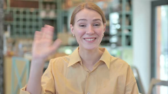 Portrait of Beautiful Young Woman Waving at the Camera