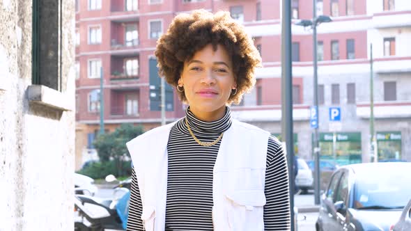 Slow motion portrait of young beautiful curly hair black woman outdoor in the city smiling healthy