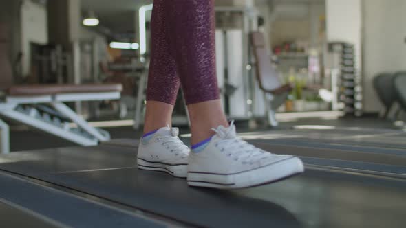 Female Legs in Sport Shoes Walking on Treadmill