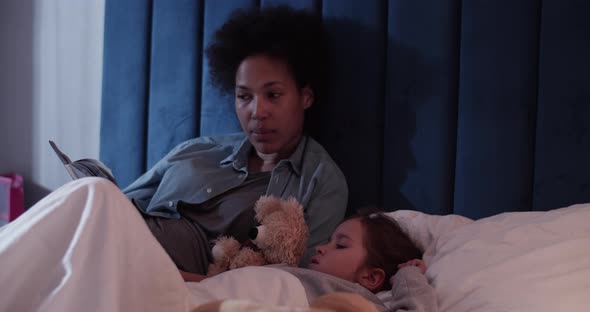 Black Mom Reading Book to Kid at Night