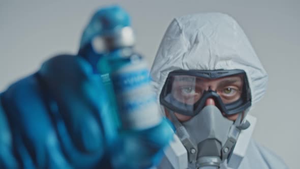 Scientists in Protective Suit and Blue Gloves Holding Vial with Safe and Effective Vaccine Against