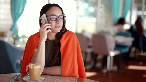 Closeup of a Successful Cute Adult Businesswoman with Glasses Uses the Phone to Talk While Sitting