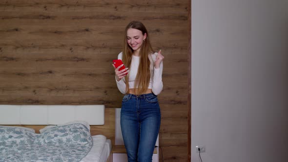 Overjoyed Smiling Young Woman Winner Jumping Dancing at Home Celebrating Mobile Phone Win Success