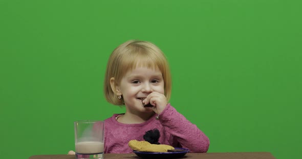 Girl Sitting at the Table and Eating Chocolate, Cookies and Drinks Cacao