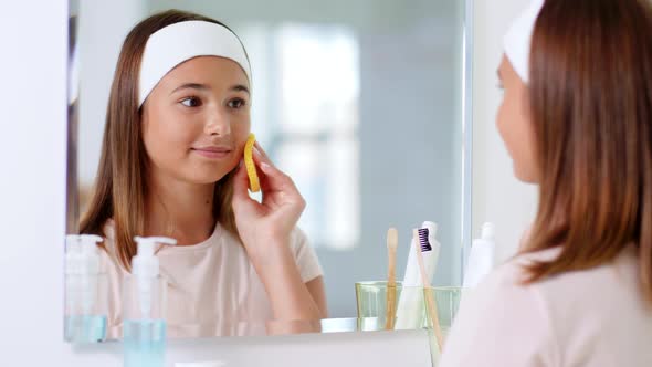 Teenage Girl Cleaning Face with Sponge at Bathroom