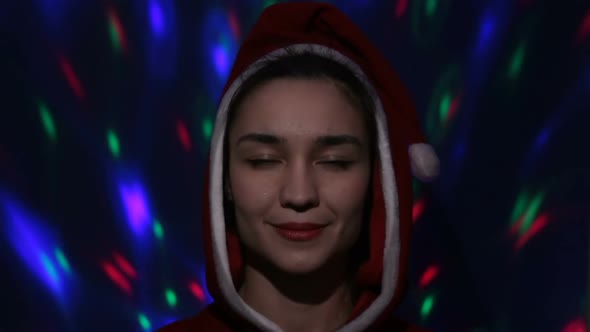 Pretty Young Woman in Santa Claus Hat Smiling and Looking Coquettishly at the Camera