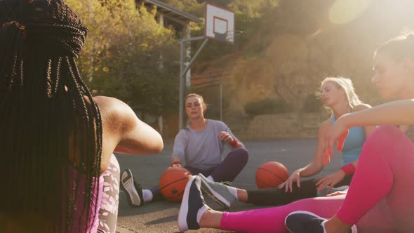 Diverse female basketball team wearing sportswear, stretching