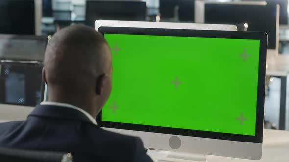 Business AfricanAmerican Man Working on Desktop Computer with Green Screen Mock Up Display in Busy