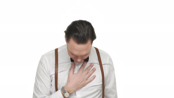Portrait of Artistic Mannered Man Wearing White Shirt and Suspenders Bowing with Hand on Chest and