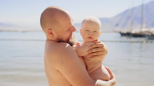 Cute Little Baby and Father Hug Boy Outside Sea Ocean