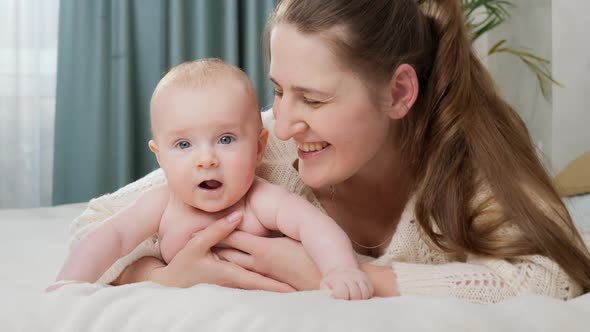 Portrait of Smiling Happy Mother Embracing Her Little Baby Boy in Bed at Morning