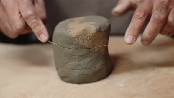 Potter Cuts Round Piece of Clay with Special String and Lifts It Side View Rotation Shooting