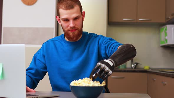 Young Man Watching a Movie in Laptop and Eating Pop Corn at Home