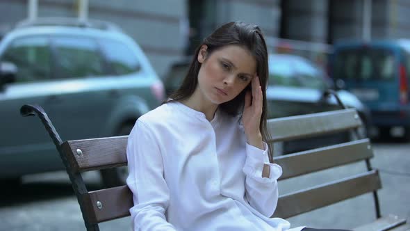 Exhausted Woman Sitting on Bench, Suffering From Migraine Pain, Health Problem