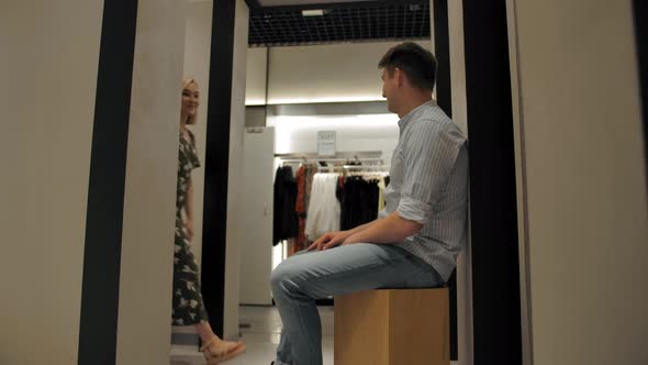 Young Guy Waiting His Girfriend Tying New Dress in Fitting Room