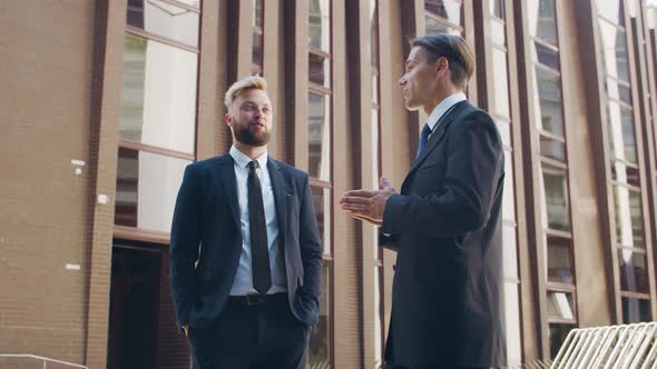 Confident businessman and his colleague in front of modern office building.