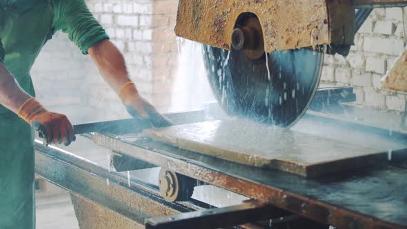 Cutting stone at the factory. Saw blade equipment sprays water on rock for cooling.