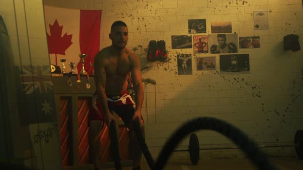 Man training with battling ropes inside a boxing studio