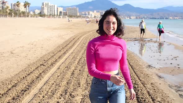 Happy Young Woman Goes Along the Coastline and Smiling