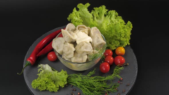 On a Black Background on a Stone Tray Dish of Dumplings with Meat