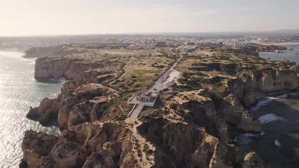 Breathtaking dolly out aerial view of lighthouse Farol da Ponta da Piedade Lagos Algarve Portugal.